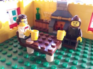 Lego room with two Lego minifigure men sitting at a table holding cups