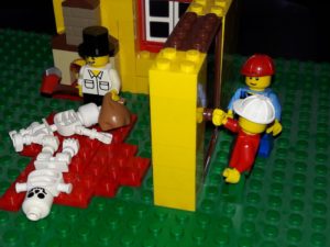 Lego room with two Lego skeletons on red tiles representing blood, Lego minifigure man holding axe and sack, two Lego minifigure construction workers outside the door